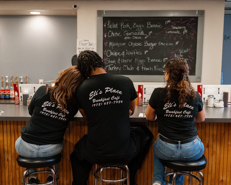 Three regulars at the counter checking the chalkboard specials