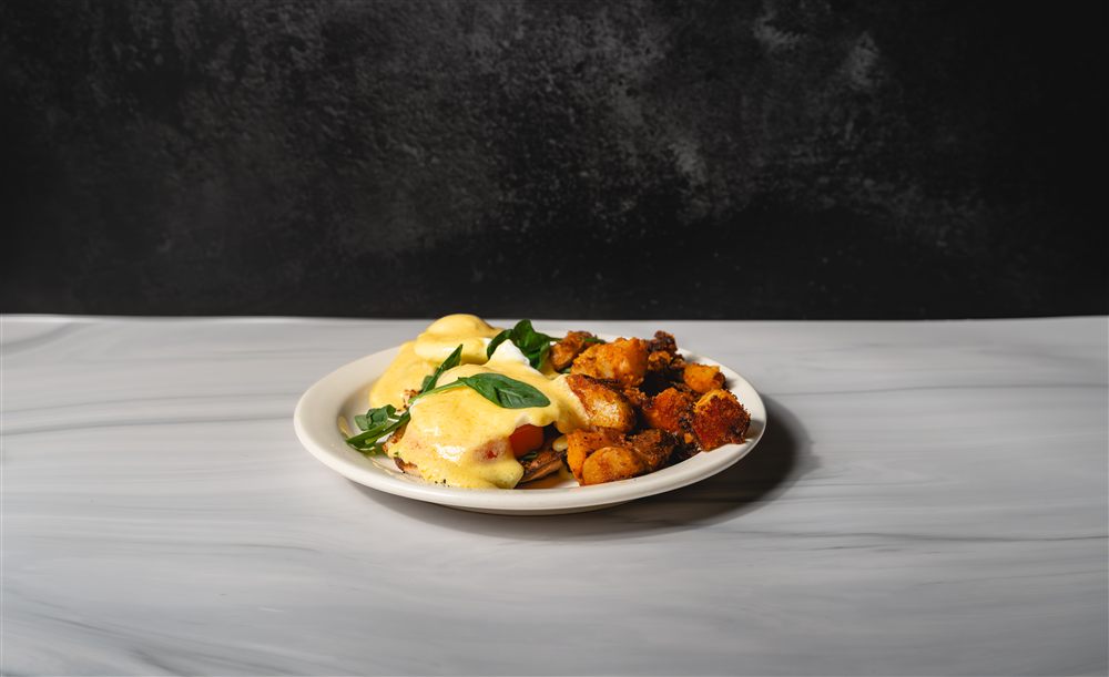 Eggs Benedict Florentine with hollandaise draped over spinach and tomato
