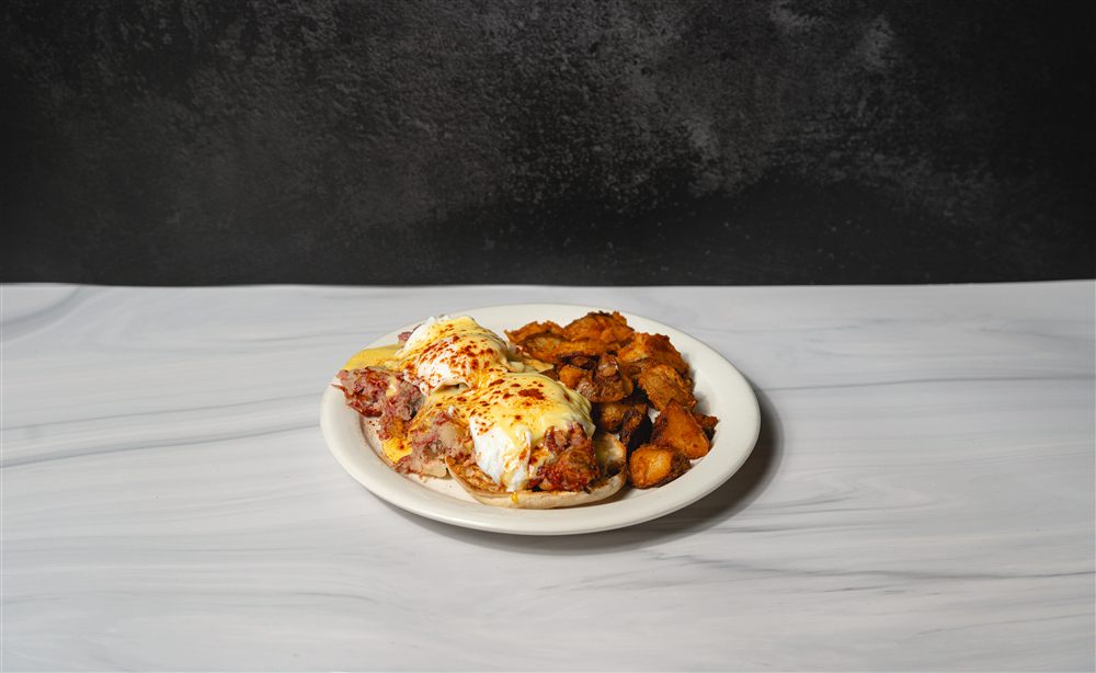 Irish eggs benedict draped in hollandaise with crispy home-fries alongside